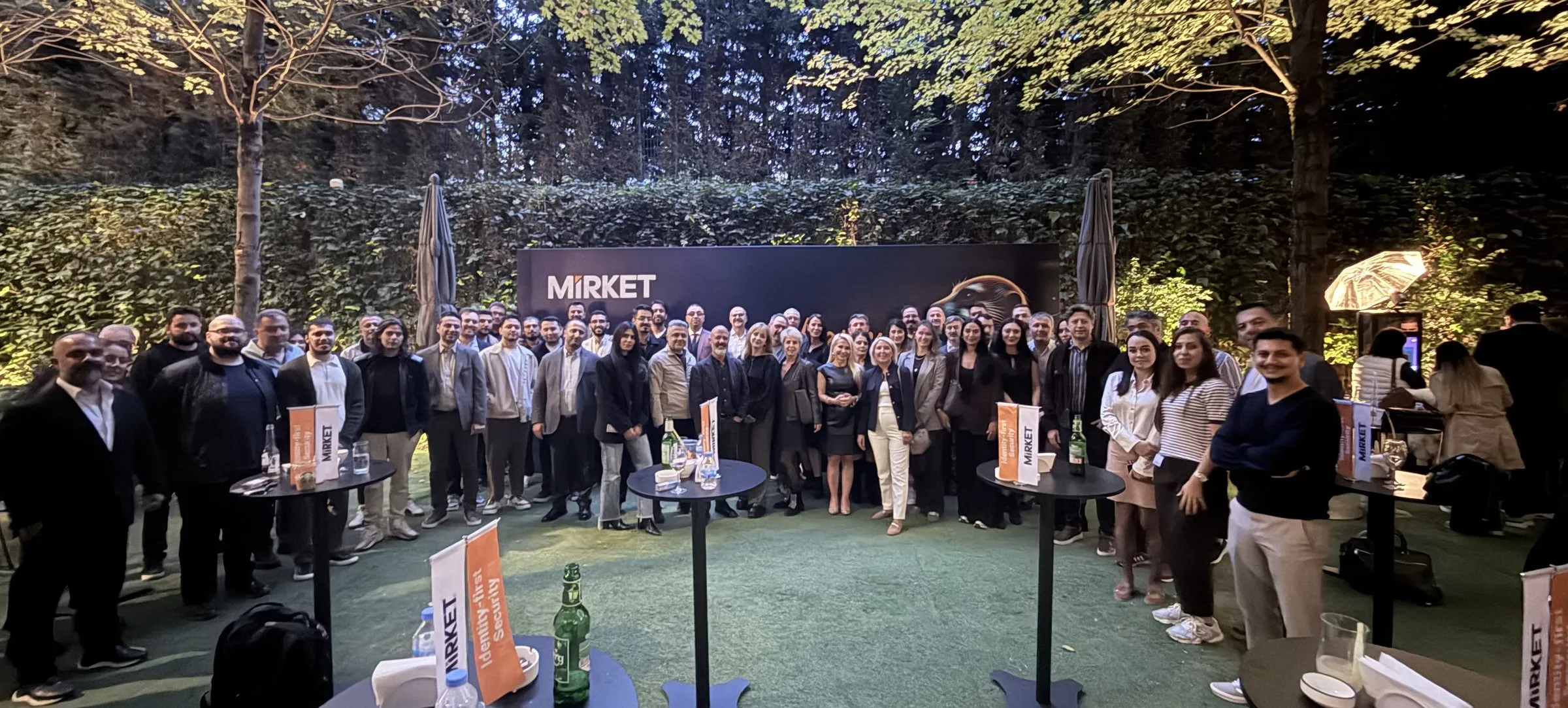 A large group gathered in front of a Mirket banner at an evening event